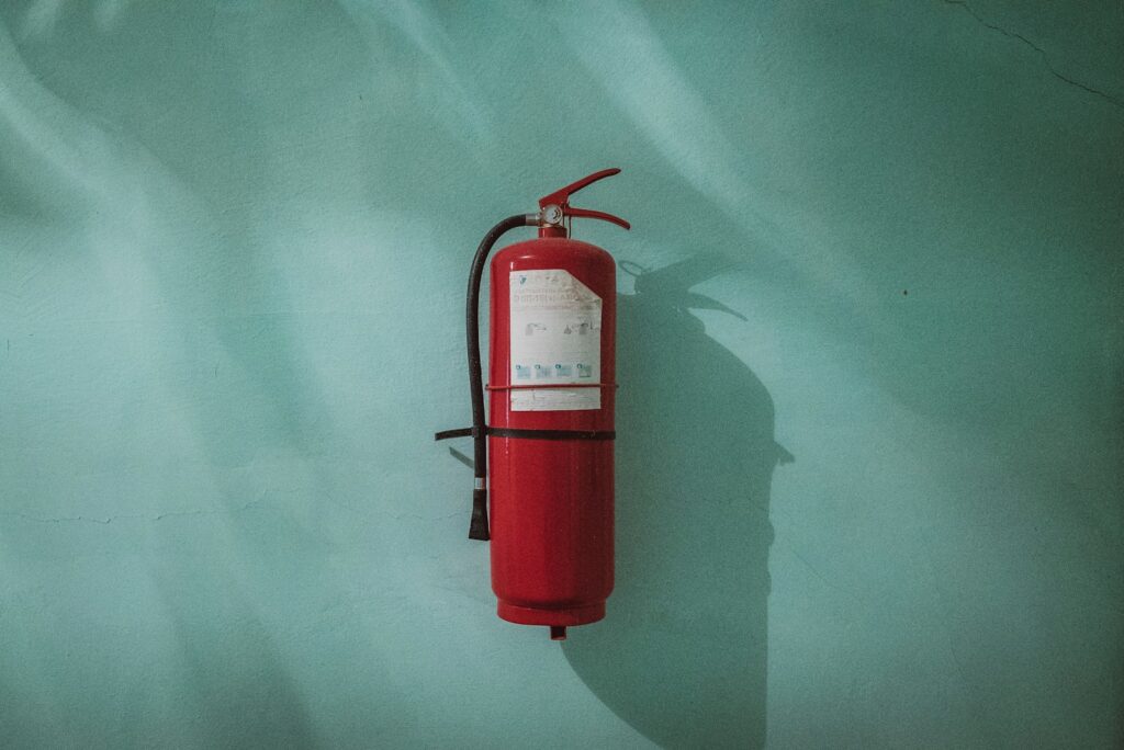 Photo by Piotr Chrobot red fire extinguisher on green wall